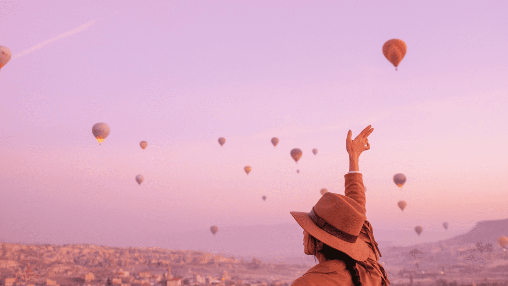 Ambition Woman Sitting and Waving Hand to Hot Air Balloons by Yunustug from Studio Turkey (Free use via Canva)